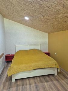 a bedroom with a bed with a yellow blanket on it at Lukas cottage in sagarejo in Sagarejo