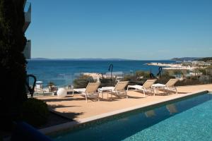 a swimming pool with chairs and a view of the ocean at Eol Apartments Split Žnjan Beach in Split