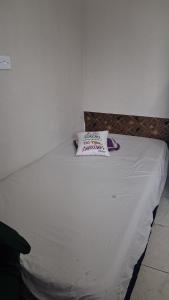 a white bed with a pillow on top of it at Kitnet quarto e cozinha ha 3min da Unifesp in São Paulo