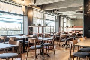 a restaurant with tables and chairs and windows at Scandic Espoo in Espoo