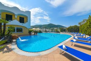 a large swimming pool with blue chairs and a building at Hotel Terme Felix in Ischia Town
