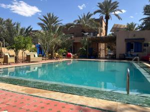 a swimming pool in a resort with palm trees at Maison La Berberina in Goulmima