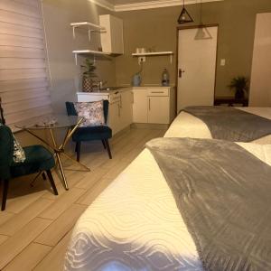 a bedroom with a bed and a table and a kitchen at Saints boutique lodge in Bloemfontein