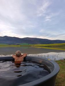 a man sitting in a bath tub next to a body of water at Bietjiedam's Campsites in Caledon +20 photos