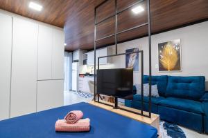 a living room with a blue couch and a tv at Studio Completo AC Piscina Pet Friendly NH in Novo Hamburgo