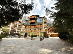a large building in a parking lot with mountains in the background at Diana 9 in Leukerbad