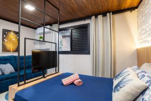 a bedroom with a blue bed and a tv at Studio Completo AC Piscina Pet Friendly NH in Novo Hamburgo +13 photos