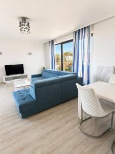 a living room with a blue couch and a table at Apartamenty Przy Latarni Kropla Bałtyku in Darlowko