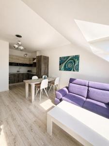 a living room with a purple couch and a table at Apartamenty Przy Latarni Kropla Bałtyku in Darlowko