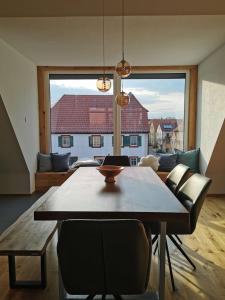 ein Esszimmer mit einem Tisch und einem großen Fenster in der Unterkunft Falken-Loft in Giebelstadt