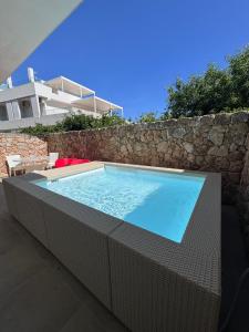 a large swimming pool sitting next to a stone wall at Venti D'Amare Suites in Polignano a Mare