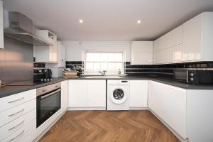 a kitchen with white cabinets and a washing machine at Bedford Retreat in Bedford