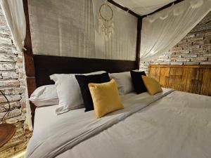 a bedroom with a bed with white sheets and yellow pillows at Santhiku Hotel & SPA in Lovina