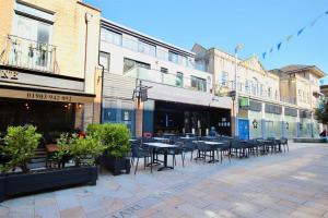 an empty street with tables and chairs and buildings at Wonderful Worthing Beach Walk Flat in Worthing