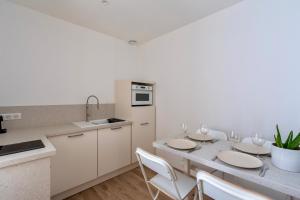 a kitchen with a table with chairs and a kitchen with white cabinets at L'escale Mourillon - Plage, Balnéo & Soleil in Toulon