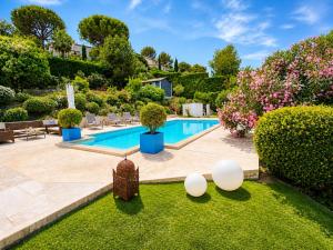 a swimming pool in a garden with bushes and trees at Villa Del Sol with Mountain Views in Vence
