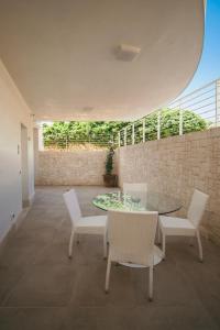 a patio with a glass table and white chairs at Venti D'Amare Suites in Polignano a Mare