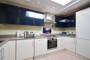 a white kitchen with blue cabinets and appliances at Wonderful Worthing Beach Walk Flat in Worthing