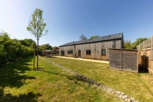 a tree in a yard next to a barn at Luxury Norfolk Barn for 12 with Hot Tub , Games Room & EV Car Port in Lenwade