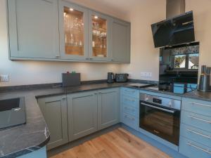 a kitchen with gray cabinets and a stove top oven at Castaway Cottage Maidens in Girvan