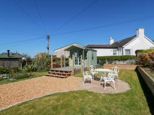 a patio with a table and chairs in a yard at Castaway Cottage Maidens in Girvan