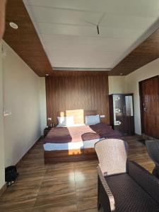 a bedroom with a large bed and two chairs at HKS Orchards Stay in Kanatal +8 photos