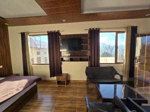 a bedroom with a bed and a couch and a table at HKS Orchards Stay in Kanatal