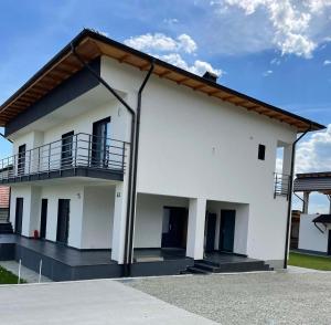 a white house with a balcony on the side at Exclusive Villa Jacuzzi & BBQ in Şerbăneşti