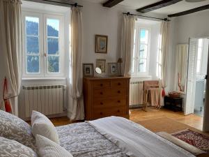 a bedroom with a bed and a dresser and windows at Le Couvent in Saint-Just-sur-Viaur