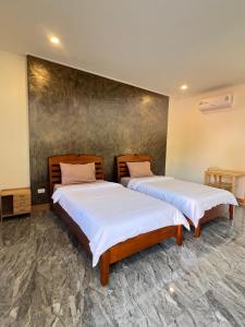 two beds in a room with white sheets at Wiang Kham Resort in Ban Na Phra That