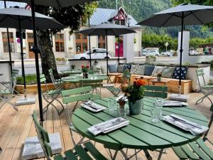 a green table with chairs and umbrellas on a patio at Langley Hotel Gustavia in Chamonix