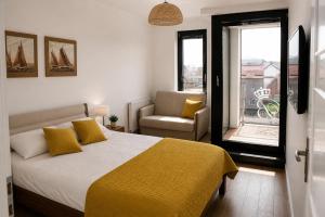 a bedroom with a bed and a chair and a window at Apartamenty Przy Latarni Kropla Bałtyku in Darlowko +19 photos