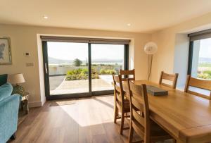 a dining room with a wooden table and a large window at The Summit - Skellig Coast in Cahersiveen +13 photos