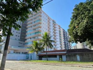 a tall building with palm trees in front of it at Atlântico 33 Guilhermina in Praia Grande