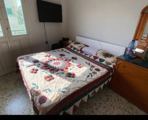 a bedroom with a bed with a flowered blanket and a dresser at Penthouse Sea Apartment in El Mîna