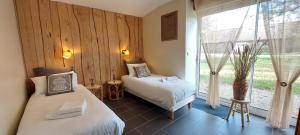 a bedroom with two beds and a large window at Gite le rémijour in Céaux-en-Couhé