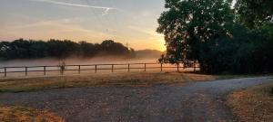 a dirt road next to a fence with fog in the background at Gite le rémijour in Céaux-en-Couhé