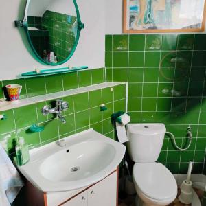 a green tiled bathroom with a toilet and a sink at House with garden For 8 people in Suwałki +11 photos