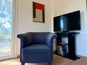 a blue chair in a living room with a television at Themis in Aghia Marina