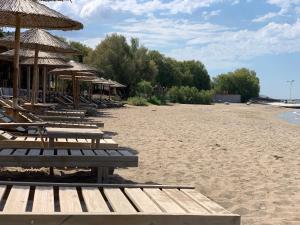 a beach with benches and straw umbrellas on it at Themis in Aghia Marina