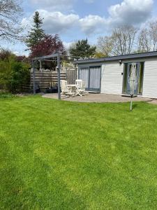a yard with a house with a bench and a gazebo at Mooi chalet op de Veluwe! in Lunteren