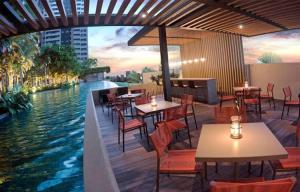 a restaurant with tables and chairs next to the water at Piscine Statio Resort Brás in São Paulo