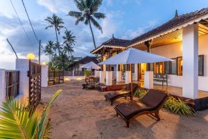 a house on the beach with chairs and an umbrella at Villa Naina, Marari beach in Alleppey