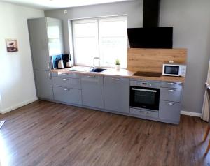 a kitchen with stainless steel appliances and a wooden floor at Reetdachhaus 1, inkl 2 Parkplätze in Fehmarn