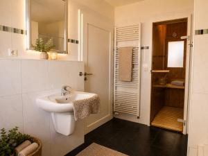 a white bathroom with a sink and a mirror at Reetdachhaus 1, inkl 2 Parkplätze in Fehmarn