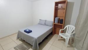 a small bedroom with a bed and a white chair at Estadia Do Vale Hospedaria União da Vitória in União da Vitória