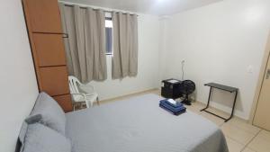 a bedroom with a bed and a chair and a window at Estadia Do Vale Hospedaria União da Vitória in União da Vitória