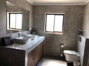 a bathroom with two sinks and a toilet and two windows at F2 Homestead in Omuthiya
