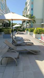 a group of lounge chairs and an umbrella at Relaxing Urban Retreat - Marina Spatial in Piapi