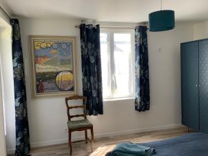 a bedroom with a chair and a window at Longère au Numéro 7 in Le Tronquay